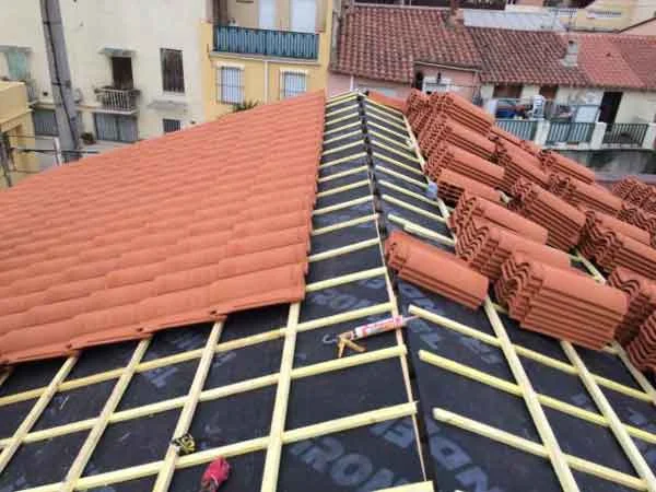 Pose de tuiles sur une toiture avec écran sous-toiture et liteaux visibles