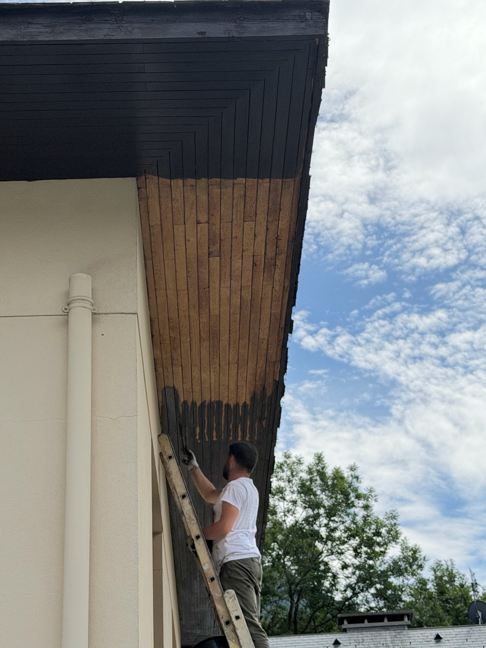 Travaux de finition sur boiseries de toiture depuis l’échelle
